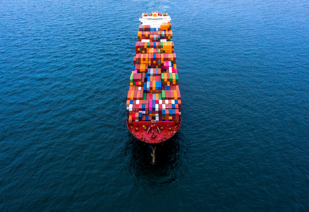 Image of a ship carrying shipping containers across the ocean
